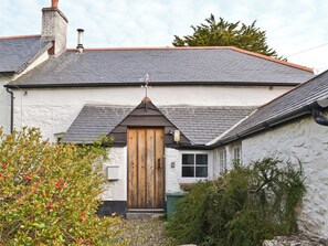 A white building with a dark roof, a wooden door, and a chimney.
