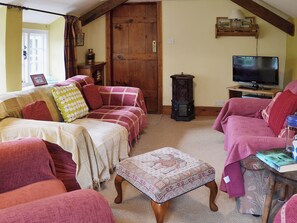 Ein gemütliches Wohnzimmer mit einer Sofagarnitur, einer Holztür, einem Fernseher und einem kleinen Tisch.