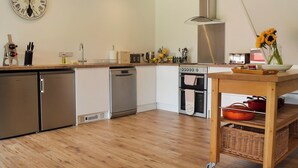 A modern kitchen with stainless steel appliances, a wooden countertop, and a wall clock. - 3 bedroom accommodation in Farnham (Farnham)