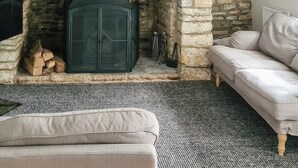A cozy living room with a stone fireplace, a sofa, and a rug. - 3 bedroom accommodation in Harmans Cross, near Swanage (Harmans Cross, near Swanage)