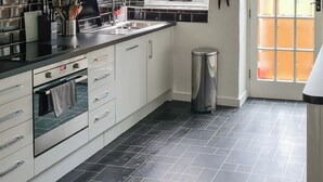 A modern kitchen with a black and white color scheme, stainless steel appliances, and a tiled floor. - 3 bedroom accommodation in Harmans Cross, near Swanage (Harmans Cross, near Swanage)