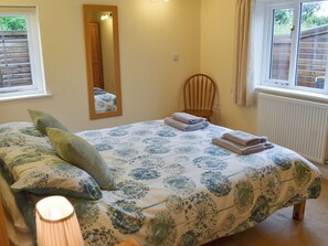 A bedroom with a bed, a chair, a mirror, and a window.