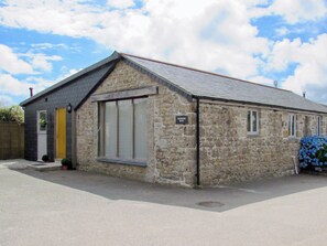A stone building with a gabled roof, a door, and a window.