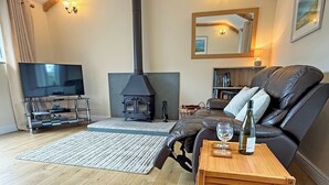 Ein Wohnzimmer mit Kamin, Ledersofa, Couchtisch aus Holz und einem Fernseher.