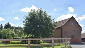 A brick building with a sloped roof, surrounded by a wooden fence and a grassy area.