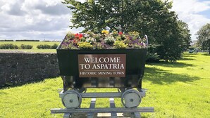 A welcome sign for Aspatria Historic Mining Town with a flower-filled cart. - 2 bedroom accommodation in Aspatria (Aspatria)