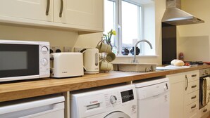A kitchen with a microwave, toaster, kettle, sink, and washing machine. - 2 bedroom accommodation in Aspatria (Aspatria)