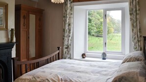 A bedroom with a large window, a wooden bed, a fireplace, and a wooden wardrobe. - 2 bedroom accommodation in St John&rsquo;s Chapel, near Stanhope (St John&rsquo;s Chapel, near Stanhope)