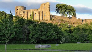 A historic stone castle with multiple towers and battlements, surrounded by lush greenery and a grassy field. - 2 bedroom accommodation in St John&rsquo;s Chapel, near Stanhope (St John&rsquo;s Chapel, near Stanhope)
