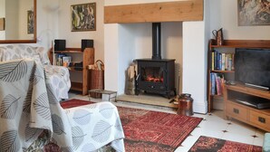 A cozy living room with a fireplace, a sofa, a bookshelf, and a television. - 2 bedroom accommodation in St John&rsquo;s Chapel, near Stanhope (St John&rsquo;s Chapel, near Stanhope)