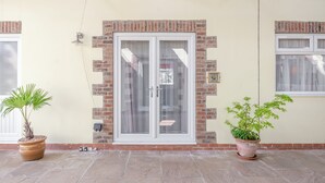Un bâtiment à la façade en briques, doté d’une porte d’entrée en verre et orné de deux plantes en pot.