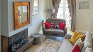 Una sala de estar con chimenea, un sillón de cuero, un sofá, una alfombra y un mapa en la pared.