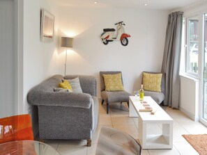 A modern living room with grey sofas, a white coffee table, and a wall-mounted scooter.