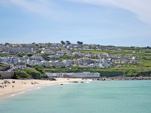 Eine Küstenstadt mit terrassenförmig angelegten Häusern, einem Strand und einem Steg.