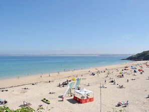 A beach with people sunbathing and swimming, tents, and a lifeguard stand.