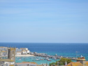 A coastal town with a prominent tower, a marina with boats, and a clear view of the sea.