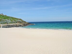A beach with a rocky cliff and a clear blue sky.