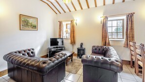 A living room with a fireplace, leather sofas, a television, and a window with curtains.