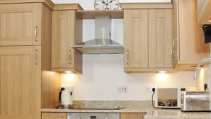 A kitchen with wooden cabinets, a stainless steel range hood, a built-in oven, a coffee maker, and a toaster. - 3 bedroom accommodation in Tickton, near Beverley (Tickton, near Beverley)