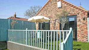 A brick house with a white fence, a small garden, and a white umbrella. - 3 bedroom accommodation in Tickton, near Beverley (Tickton, near Beverley)