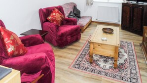 Ein Wohnzimmer mit einem roten Samtsofa, einem Holztisch und einem gemusterten Teppich.
