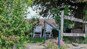 Ein Garten mit Steintreppe zu einer Sitzgelegenheit mit zwei weißen Stühlen.