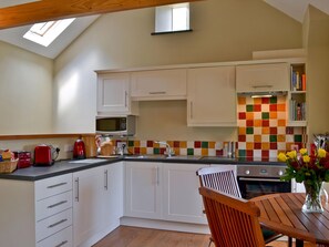 A kitchen with white cabinets, a microwave, a toaster, and a colorful backsplash.