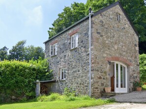 A stone building with a sloped roof, a visible chimney, and a door with glass panels.