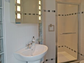A bathroom with a white sink, a glass shower enclosure, and a mirror above the sink.