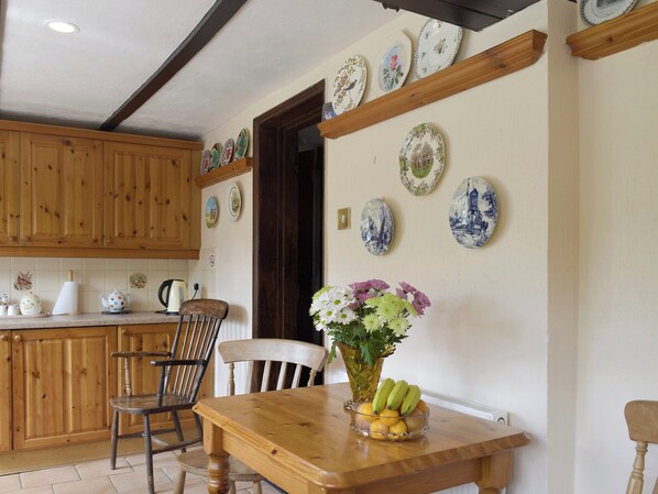A kitchen with wooden cabinets, a dining table with chairs, and decorative plates on the wall.