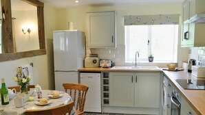 A kitchen with a refrigerator, dishwasher, and a window with a view of greenery. - Acorn Cottage - UKC1812 (North Perrott, near Crewkerne)