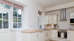 Una cocina moderna con armarios blancos, encimera de madera, campana extractora de acero inoxidable y horno empotrado.