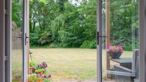 Une porte vitrée donnant sur un jardin avec une pelouse et des plantes en pot.