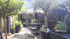 A patio area with a table and chairs, surrounded by potted plants and a wooden fence. - This is the ideal base for discovering and exploring Dorset. (East Burton, near Wool)