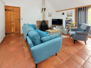 Ein Wohnzimmer mit Sofa, Sessel, Fernseher, Kamin und Bücherregal.