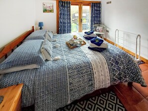 A neatly made bed with patterned bedding, a tray with tea cups and a teapot, and a small decorative item on the nightstand.