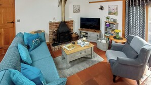 A living room with a sofa, armchair, coffee table, fireplace, TV, and shelves with decorative items. - This is the ideal base for discovering and exploring Dorset. (East Burton, near Wool)