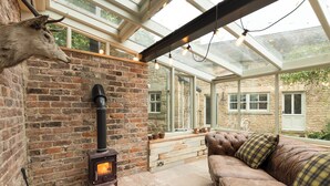 A cozy room with a brick fireplace, a leather sofa, and a glass ceiling. - 3 bedroom accommodation in Riding Mill, near Corbridge (Riding Mill, near Corbridge)