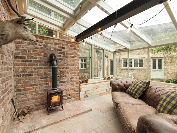 A cozy room with a brick fireplace, a leather sofa, and a glass ceiling.