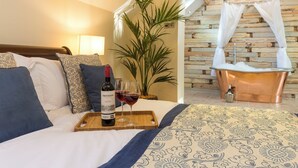 A bedroom with a bed, a tray with a wine bottle and glasses, a potted plant, and a bathroom with a bathtub. - 3 bedroom accommodation in Riding Mill, near Corbridge (Riding Mill, near Corbridge)