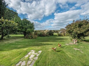 A well-maintained garden with a clear path, lush greenery, and a rustic stone structure. - Red Squirrel Lodge - UKC677 (Wootton, near Ryde)