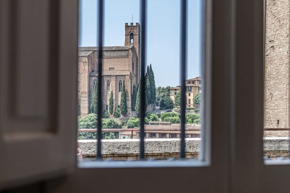 A view through a window of a historic building with a prominent tower and arched windows. - SAN DOMENICO - Two Bedroom Apartment, Sleeps 4 (Siena)