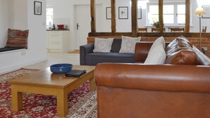 A spacious living area with a wooden ceiling, a sofa set, a coffee table, and a red patterned rug. - 4 bedroom accommodation in Ashperton, near Ledbury (Ashperton, near Ledbury)