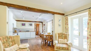 A spacious living area with a sofa, a chair, and a dining table. A kitchen is visible in the background. - COTTAGE IN THE POND W43212 (Garton, near Hornsea)