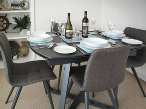 A dining table set with plates, glasses, and a bottle.