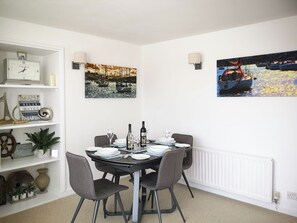 A dining area with a round table, chairs, and a white radiator.