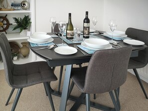 A dining table set with plates, glasses, and a bottle. - Seascape - St Catherine's Court (Fowey)