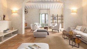 A spacious living room with a high ceiling, a fireplace, and a view through an archway.