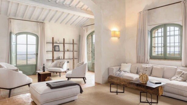 A spacious living room with a high ceiling, large windows, and a cozy seating area.