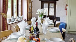 A dining table set with white plates, bowls, and a variety of food items including cheese and olives.